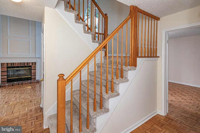 stairs with a fireplace, baseboards, and a textured ceiling