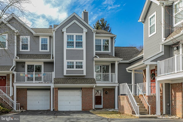 townhome / multi-family property featuring aphalt driveway, roof with shingles, brick siding, a chimney, and a garage