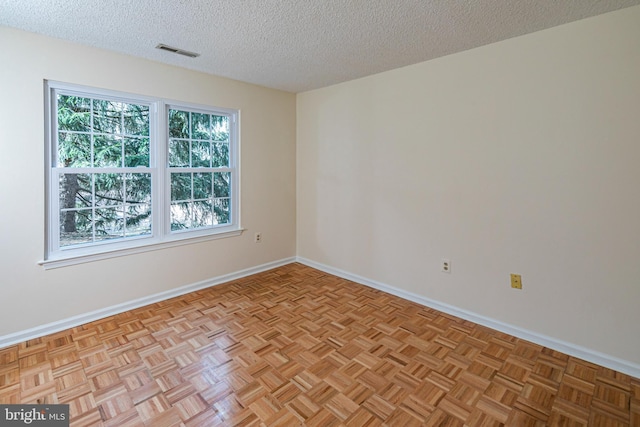 empty room featuring baseboards, visible vents, and a textured ceiling