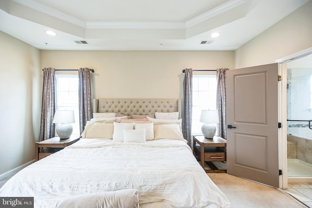 bedroom featuring a tray ceiling, multiple windows, and visible vents