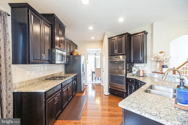 kitchen featuring light wood-type flooring, a sink, tasteful backsplash, recessed lighting, and appliances with stainless steel finishes