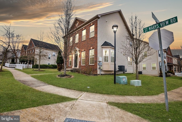 view of front of house featuring cooling unit, brick siding, and a front yard