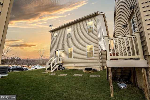 back of property with central air condition unit and a lawn
