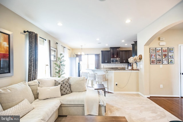 living room featuring recessed lighting, baseboards, and arched walkways