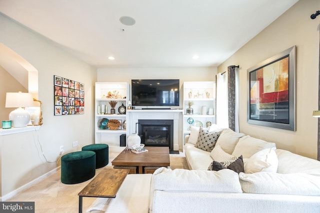 living room with a glass covered fireplace, recessed lighting, carpet, and baseboards