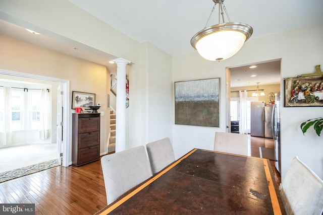 dining area featuring stairway, wood-type flooring, plenty of natural light, and ornate columns
