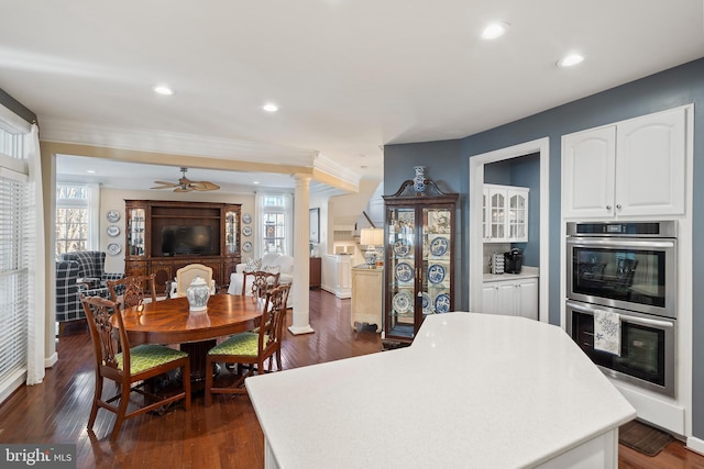 kitchen featuring dark wood-style floors, double oven, white cabinetry, a kitchen island, and ornate columns