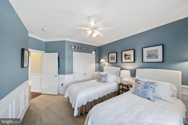 bedroom featuring ceiling fan, a wainscoted wall, carpet floors, a closet, and crown molding