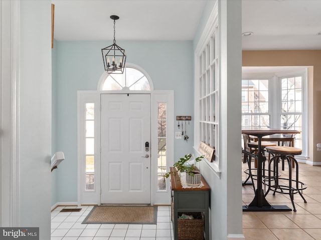 foyer entrance featuring baseboards, a notable chandelier, and light tile patterned flooring