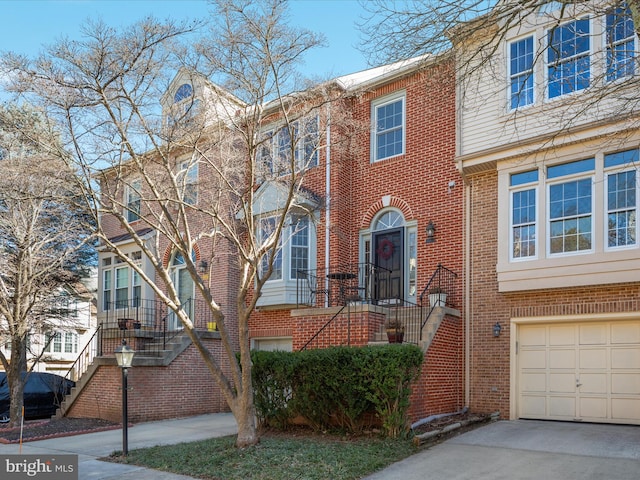 multi unit property with a garage, driveway, stairs, and brick siding