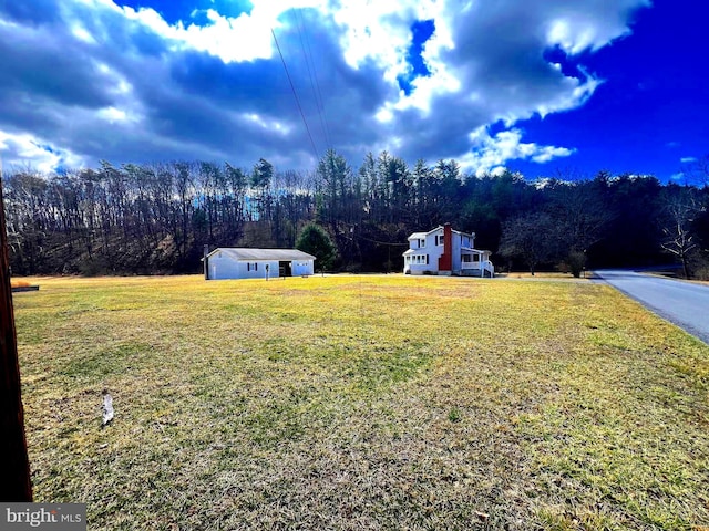 view of yard featuring a wooded view and an outbuilding