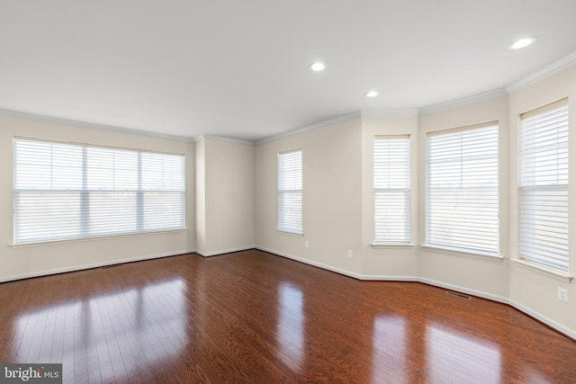 empty room featuring dark wood-style floors, visible vents, baseboards, and crown molding