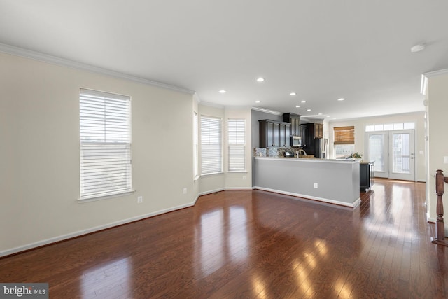 unfurnished living room with dark wood-style floors, recessed lighting, ornamental molding, and baseboards