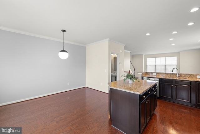 kitchen featuring dark wood-type flooring, hanging light fixtures, a sink, and light stone countertops