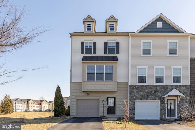 view of property featuring driveway, stone siding, and a garage