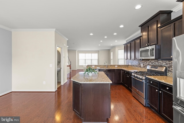 kitchen featuring dark wood-style floors, stainless steel appliances, decorative backsplash, a kitchen island, and light stone countertops