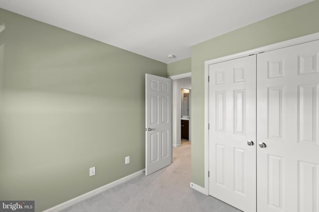 unfurnished bedroom featuring a closet, light colored carpet, and baseboards