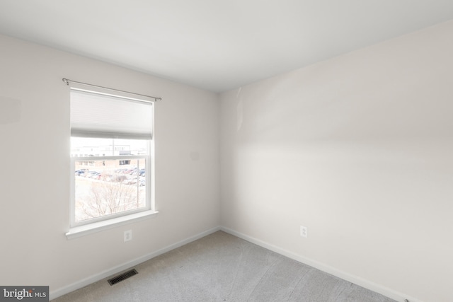 spare room with carpet floors, visible vents, and baseboards