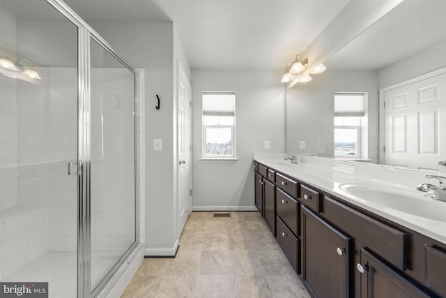 bathroom featuring double vanity, a shower stall, and a sink