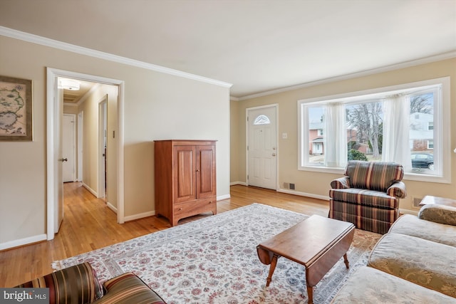 living room featuring ornamental molding, light wood-type flooring, visible vents, and baseboards