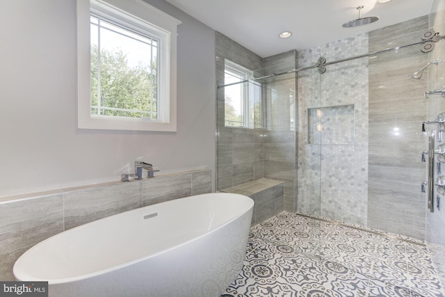 full bathroom featuring tile patterned flooring, a freestanding bath, a shower stall, and tile walls