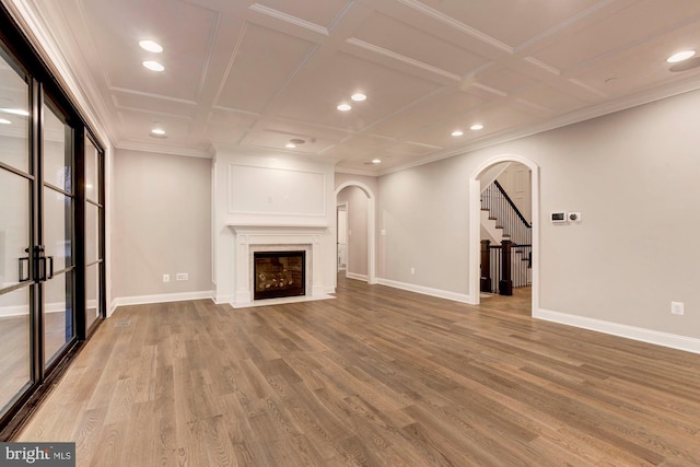 unfurnished living room featuring arched walkways, light wood-style flooring, a fireplace with flush hearth, coffered ceiling, and baseboards