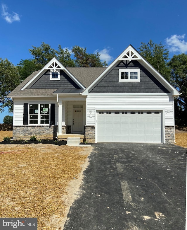 craftsman-style house featuring aphalt driveway, stone siding, and an attached garage