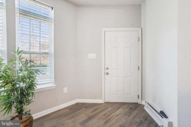 foyer entrance with a baseboard radiator, baseboards, and dark wood-type flooring