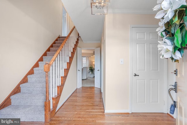 entrance foyer featuring ornamental molding, stairway, light wood-style flooring, and baseboards