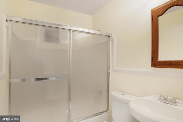 bathroom with an enclosed shower, a sink, toilet, and tile walls