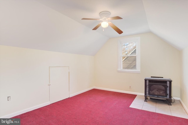 bonus room featuring light colored carpet, a ceiling fan, a wood stove, vaulted ceiling, and baseboards