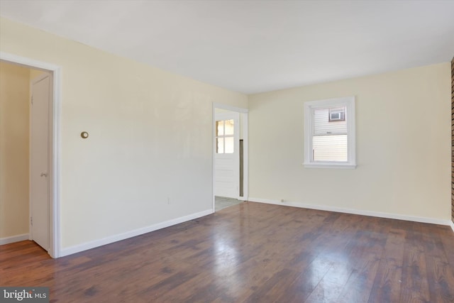 spare room with baseboards and dark wood-type flooring