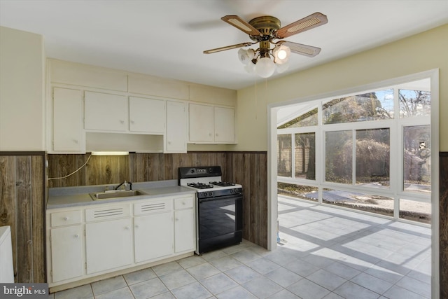 kitchen featuring white cabinets, wainscoting, range with gas cooktop, light countertops, and a sink