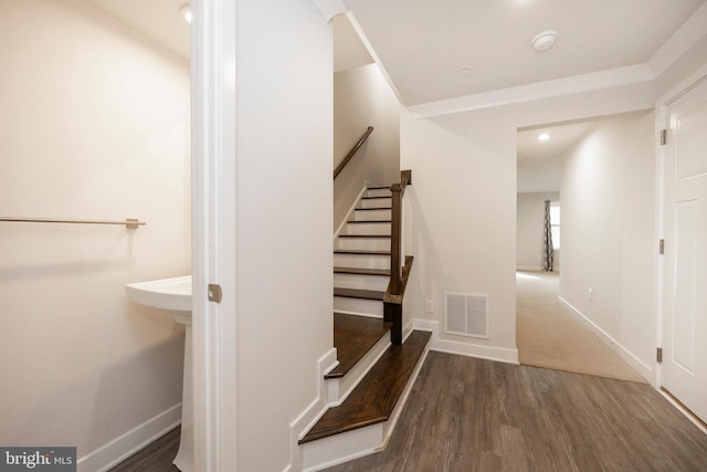 staircase with baseboards, visible vents, and wood finished floors