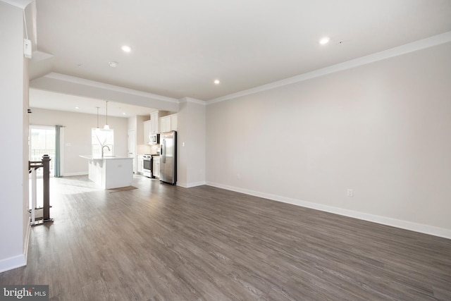 unfurnished living room with ornamental molding, recessed lighting, dark wood finished floors, and baseboards