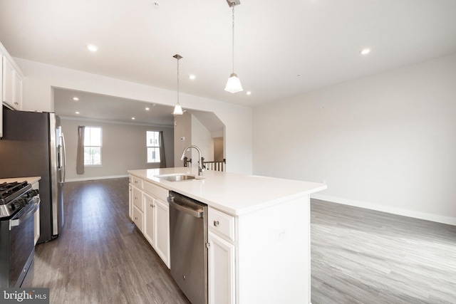 kitchen featuring a sink, white cabinets, open floor plan, appliances with stainless steel finishes, and a center island with sink