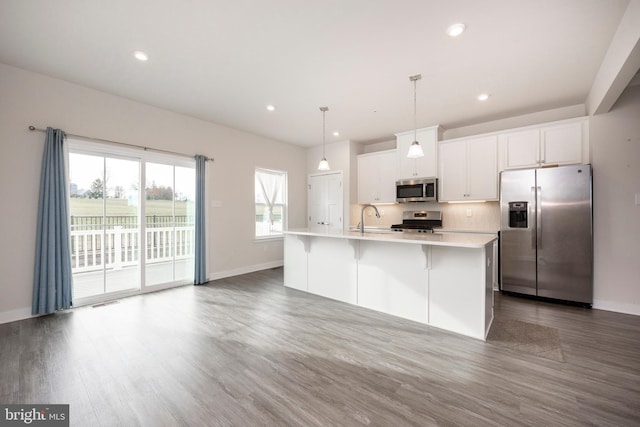 kitchen featuring white cabinetry, light countertops, appliances with stainless steel finishes, an island with sink, and pendant lighting