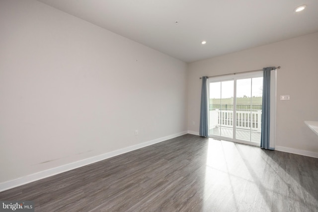 empty room featuring baseboards, dark wood-type flooring, and recessed lighting