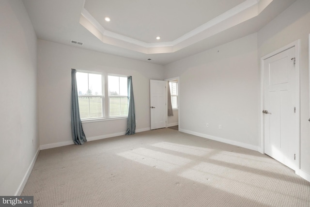 unfurnished bedroom featuring recessed lighting, light colored carpet, visible vents, baseboards, and a tray ceiling