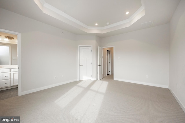 unfurnished bedroom featuring recessed lighting, a raised ceiling, light carpet, and baseboards