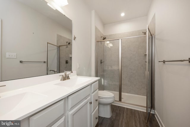 bathroom featuring double vanity, wood finished floors, a sink, and toilet