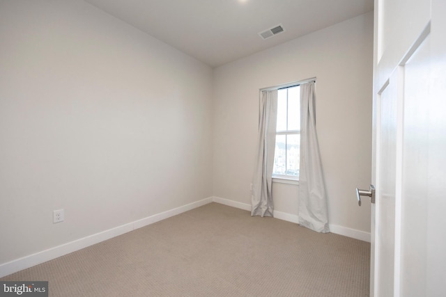 unfurnished room with baseboards, visible vents, and light colored carpet