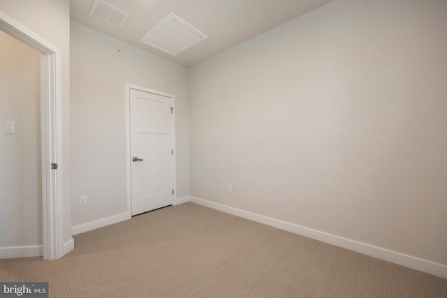 spare room with attic access, light carpet, visible vents, and baseboards