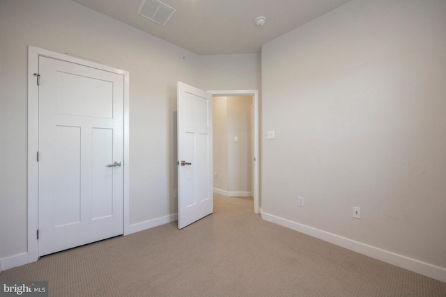 unfurnished bedroom featuring light carpet, visible vents, and baseboards