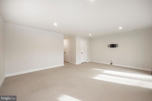 spare room featuring recessed lighting, light colored carpet, and baseboards