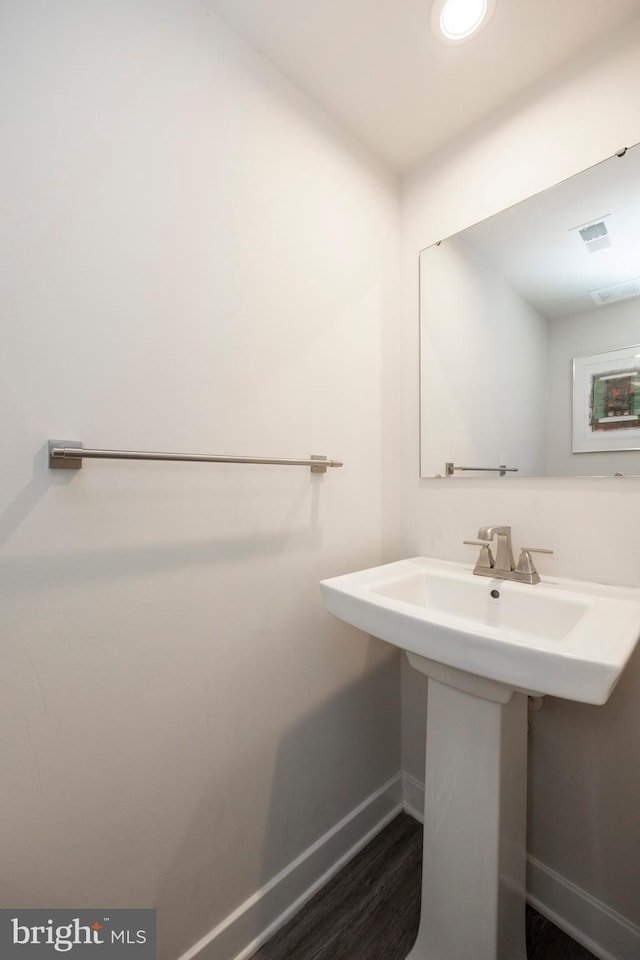 bathroom with a sink, wood finished floors, visible vents, and baseboards