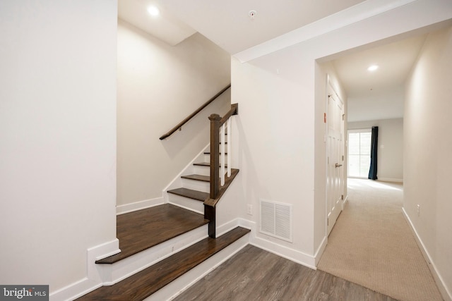 stairway featuring baseboards, visible vents, wood finished floors, and recessed lighting