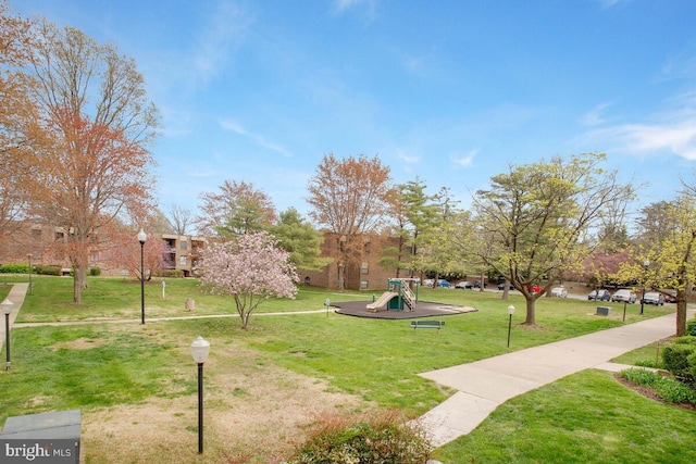 view of property's community with a lawn and playground community