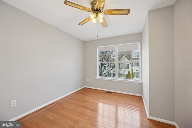 unfurnished room with a ceiling fan, wood-type flooring, visible vents, and baseboards