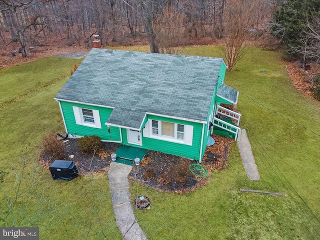 view of front of house featuring roof with shingles, a chimney, and a front lawn